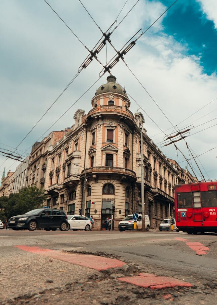 A bustling street corner in Belgrade, Serbia featuring a historic building with a tram passing by.