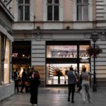 A lively street in Belgrade featuring a Spanish flag and historic architecture.
