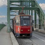 A red tram travels across a bridge under a blue sky in Belgrade, Serbia.