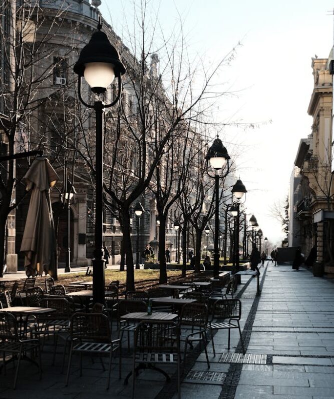 A serene street scene in Belgrade with empty outdoor cafe tables and classic architecture.