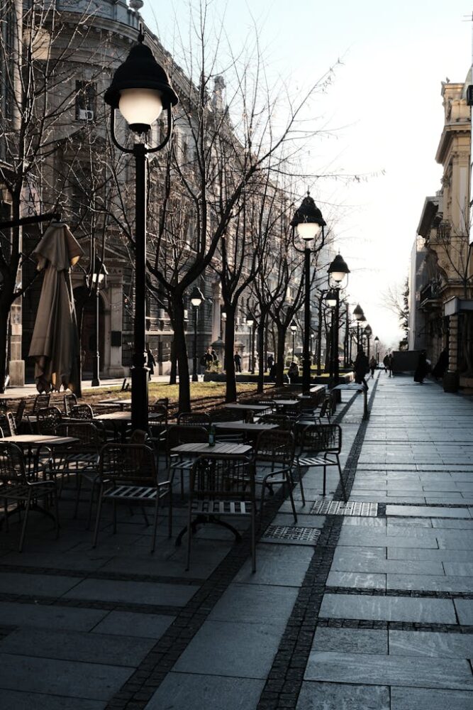A serene street scene in Belgrade with empty outdoor cafe tables and classic architecture.