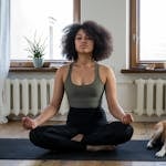 A woman practices yoga at home with her Shiba Inu dog, embracing a relaxing morning.