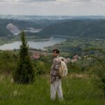 A young man with a backpack takes in the stunning view of the Serbian countryside, symbolizing adventure.