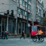 City street view in Belgrade with a red tram and cyclist crossing at an intersection.