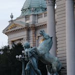 Detailed view of the House of National Assembly in Belgrade with a dramatic horse sculpture in front.