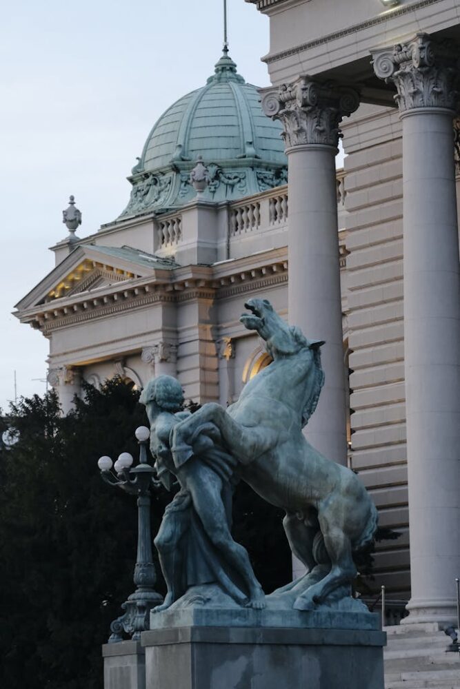 Detailed view of the House of National Assembly in Belgrade with a dramatic horse sculpture in front.