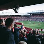 Fans cheer as players take the field at a vibrant football stadium, creating an electric atmosphere.