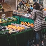 Lively city market stall displaying diverse fresh fruits. A customer browses.