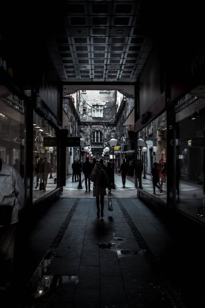 Moody alleyway in Belgrade's historic district with silhouettes of people walking, offering a glimpse of urban life.